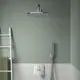 Weiße Wand mit Dusche und Chrom-Wasserauslass. An einer Leiter hängen grüne Handtücher. Ideal Standard Sanitärarmatur an der Wand.